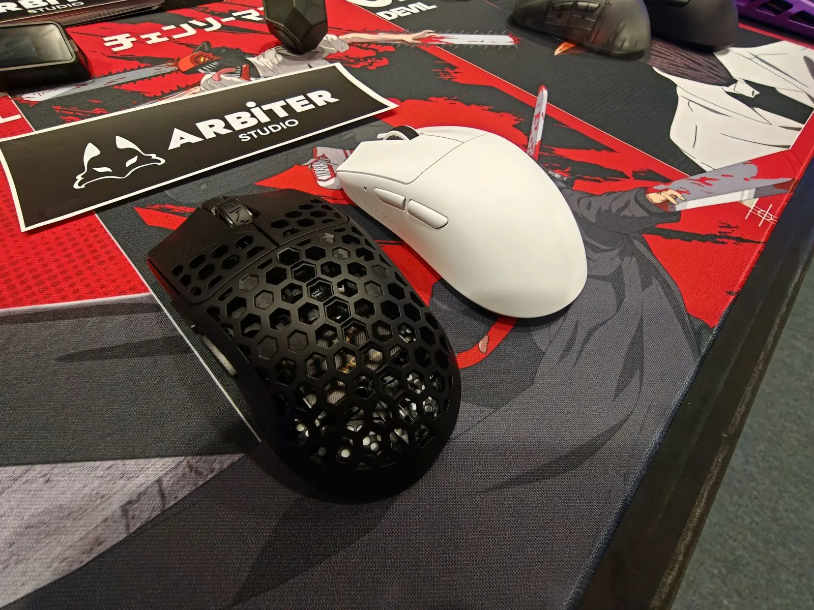 Arbiter Studioの展示卓に並んだ黒いハニカム外装のマウスと白いマウス